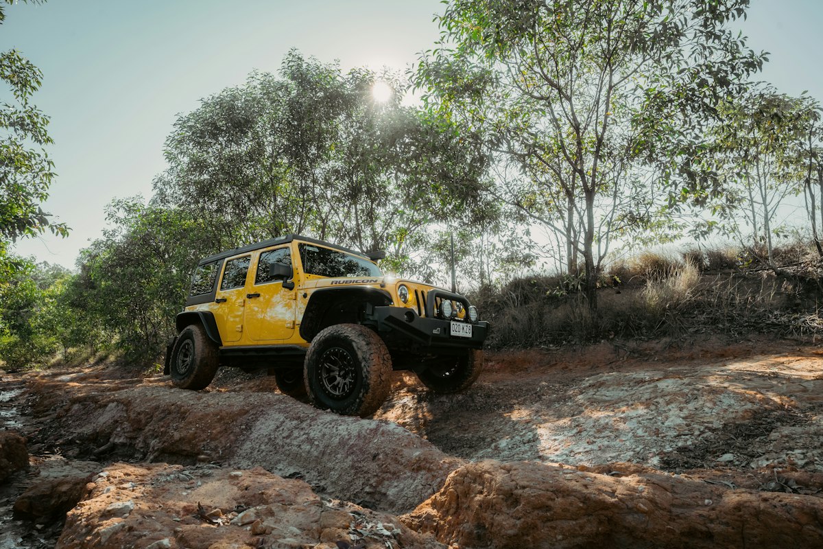 Yellow Jeep Wrangler off-road on a dirt trail