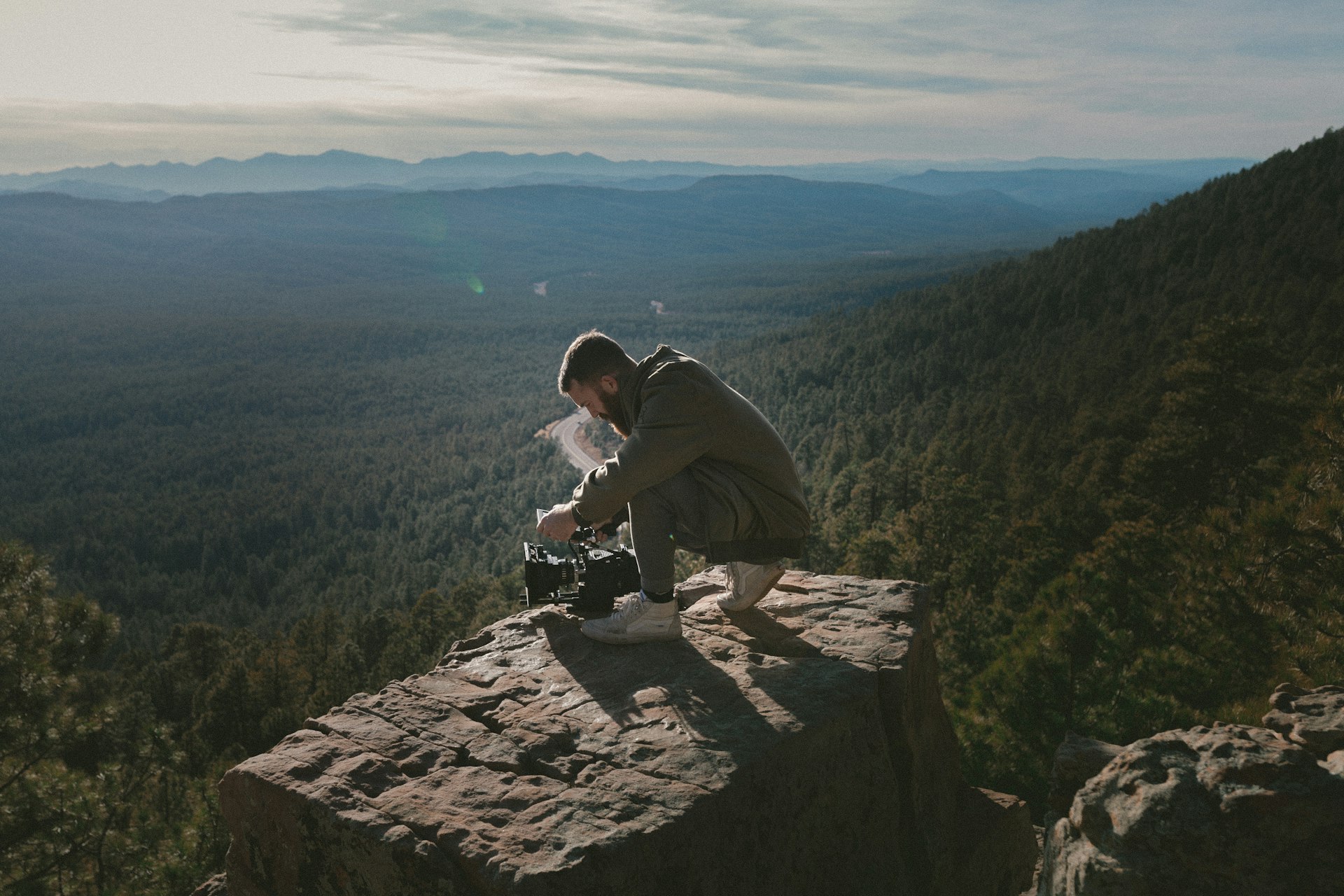 Guest photographing a wide valley view from a cliff edge