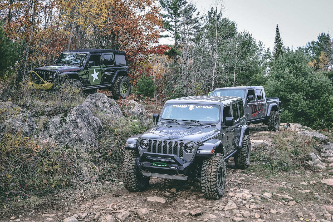 Two off-road jeeps driving together on a rocky forest trail